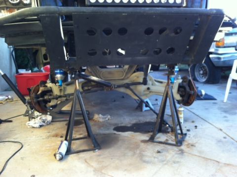 1995 Ford Bronco - The underside of a vehicle is being worked on, with the suspension components clearly visible and supported by jack stands.