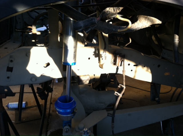 Close-up of a vehicle's suspension with a blue and silver shock absorber and tan frame