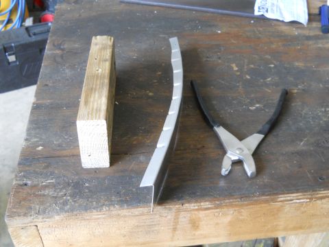 1992 Ford Bronco - Tools and a metal part laid out on a wooden workbench surface.
