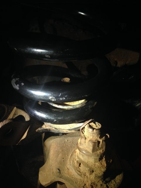 1996 Ford Bronco - This image shows a close-up view of a vehicle's suspension system, focusing on the coil spring and ball joint.