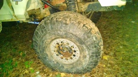 1979 Ford F-150 - Close-up of a heavily used off-road tire and suspension components on a muddy vehicle.