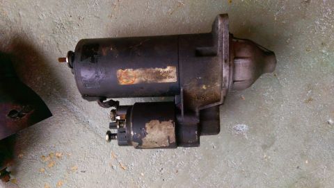 1989 BMW 3 Series - A used starter motor is shown, with visible labels and electrical connections, on a textured floor.