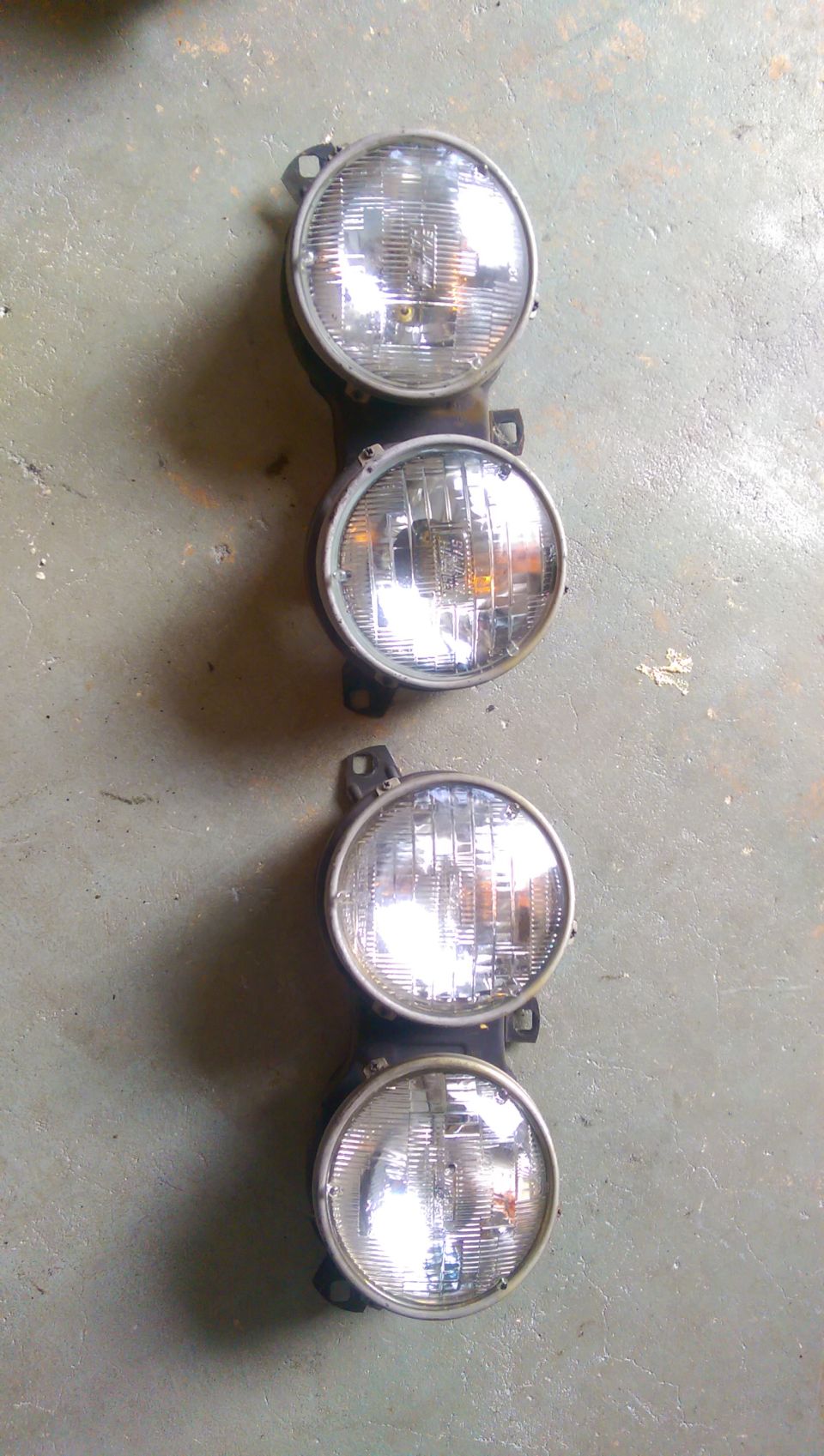 Two pairs of round headlights mounted vertically on a black bracket