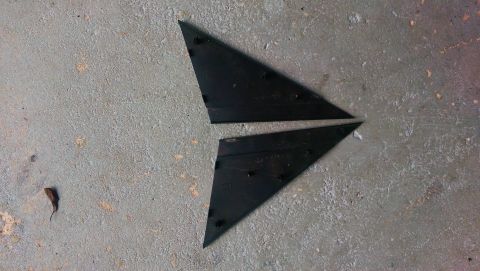 1989 BMW 3 Series - Two black triangular plastic trim pieces are shown lying on a concrete surface.