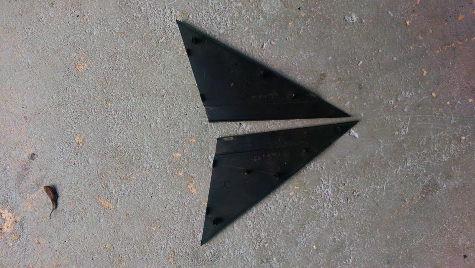 Two black triangular plastic trim pieces on concrete