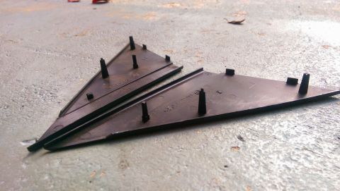1989 BMW 3 Series - Two black plastic trim pieces with mounting posts are shown on a concrete surface.