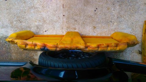 1989 BMW 3 Series - A yellow foam car seat cushion is shown, with a tire and other car parts visible underneath.
