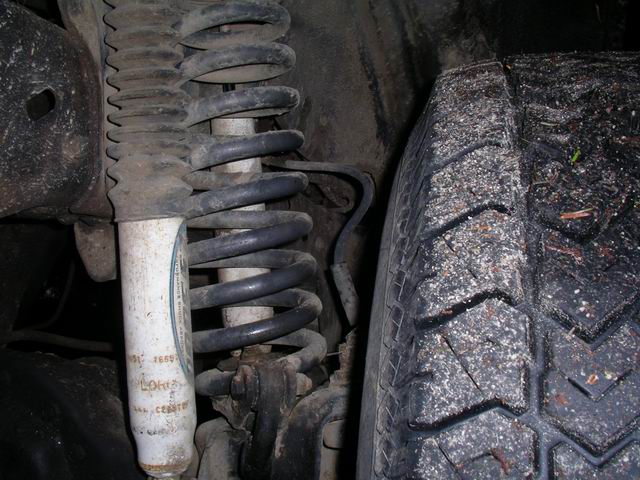 Front suspension part with coil spring and shock absorber, visible text on shock