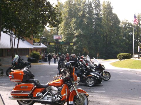 2011 Harley-Davidson Elec Gld Police - Motorcycles are parked in a lot near a general store and an archway that reads 'Deal's Gap'.
