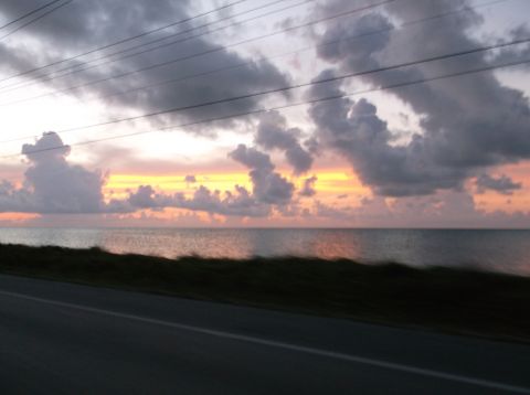 2011 Harley-Davidson Elec Gld Police - A dramatic sunset over the ocean, with dark clouds and power lines silhouetted against the colorful sky.