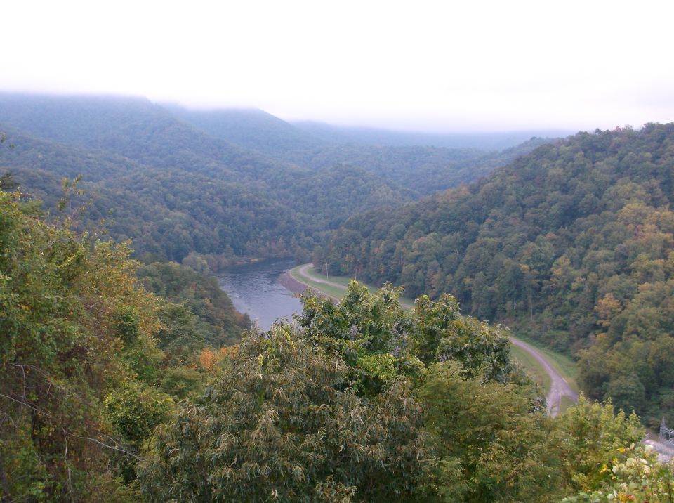 Misty mountain valley with a winding river and road