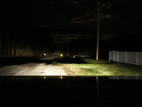 2008 Hyundai Accent - The headlights illuminate a dark, rural road at night, casting reflections on the wet surface.