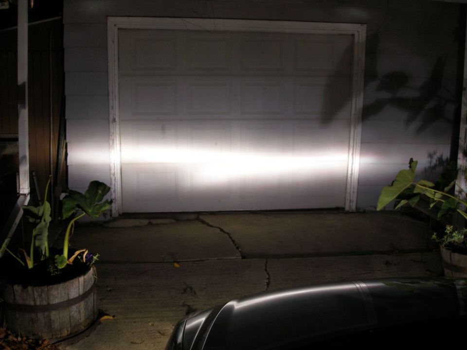 Car front with headlights on, pointed at a garage door