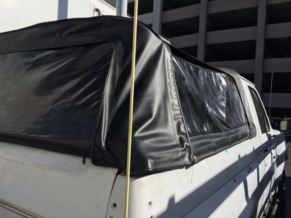 Close-up of black vinyl soft top with zippered windows on a white SUV