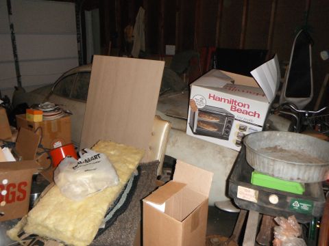 1969 Volkswagen Karmann Ghia - Interior view of a car in a cluttered garage, surrounded by various items and storage boxes.