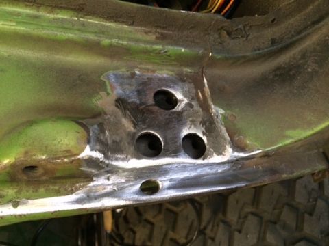1988 Suzuki Samurai - Close-up view of a green metal frame section with drilled holes and welding marks, suggesting repair or modification.