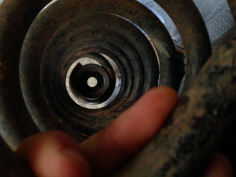 1996 Ford Bronco - A close-up view of a rusty coil spring, possibly part of a suspension system.