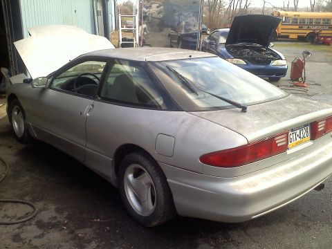 1993 Ford Probe - A silver 1993 Ford Probe GT is parked with its hood open, alongside another vehicle and a school bus.