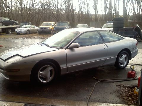 1993 Ford Probe - A silver 1993 Ford Probe coupe is seen from a three-quarter front angle in an outdoor lot with other vehicles.