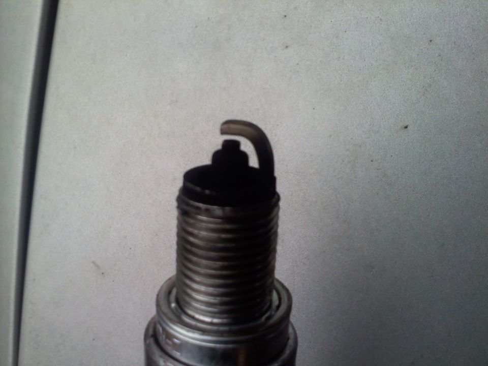 Close-up of a used spark plug with carbon buildup on the electrode