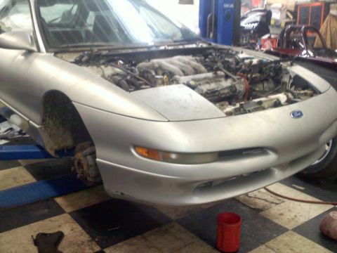 1993 Ford Probe - A silver 1993 Ford Probe GT coupe is shown with its hood open, revealing the engine, while on a lift in a garage.