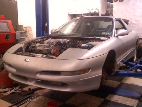 1993 Ford Probe - A silver 1993 Ford Probe GT is shown on a lift in a garage with its hood open, revealing the engine.