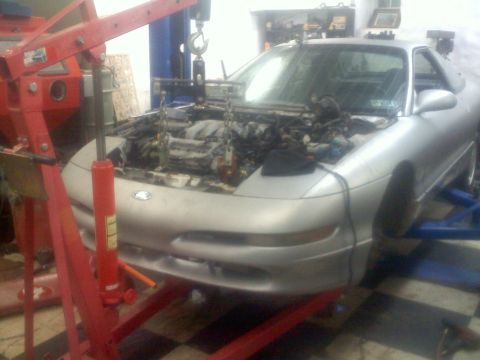 1993 Ford Probe - Silver 1993 Ford Probe coupe undergoing engine removal on a lift.