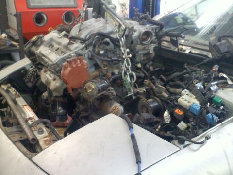 1993 Ford Probe - Engine removal in progress, revealing the intricate network of hoses and wires within the engine compartment.