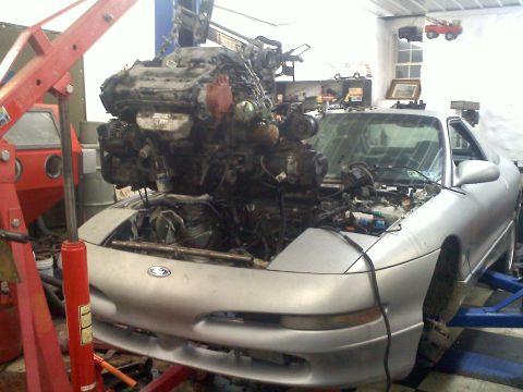 1993 Ford Probe - Engine removal in progress on a 1993 Ford Probe GT, supported by a red engine hoist.