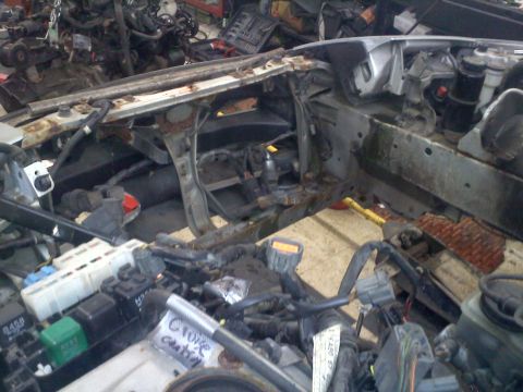 1993 Ford Probe - The front end of a car is disassembled, revealing the engine bay and various electrical components.