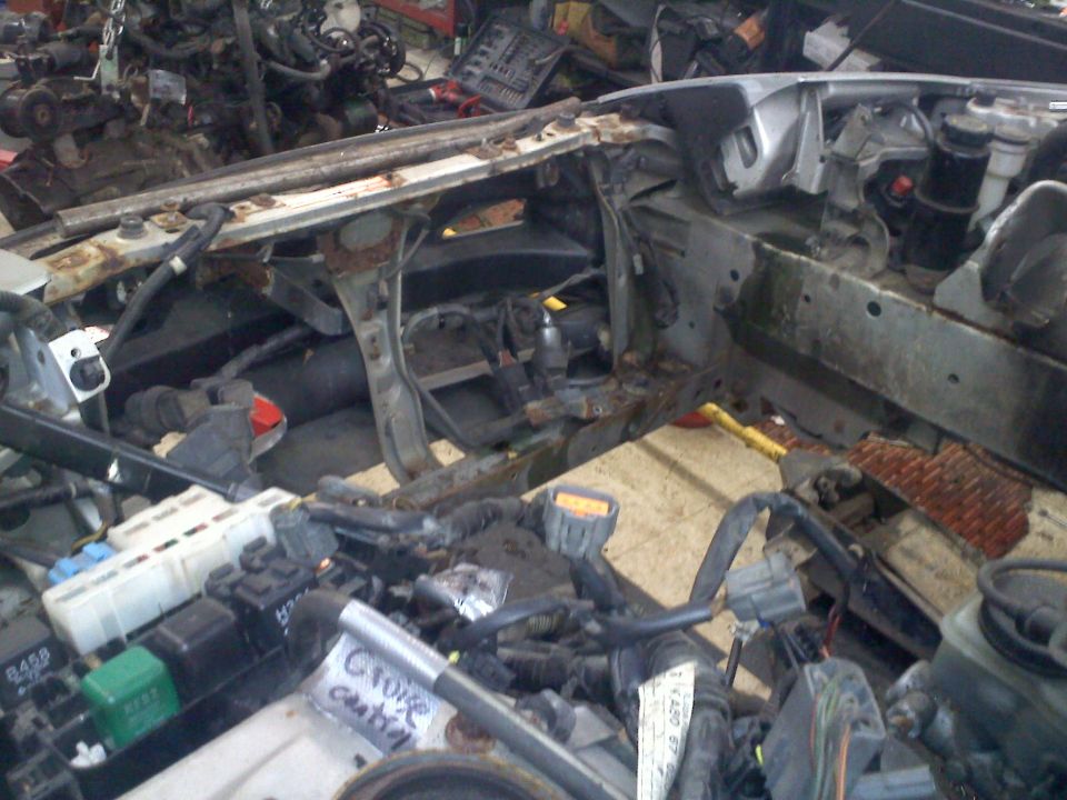 Car engine bay with parts removed, showing wiring and frame. Some labels are visible