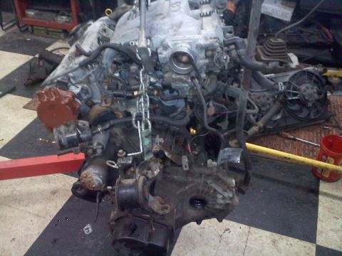 1993 Ford Probe - Engine assembly, likely removed from a vehicle, is shown with its transmission attached and suspended for work.