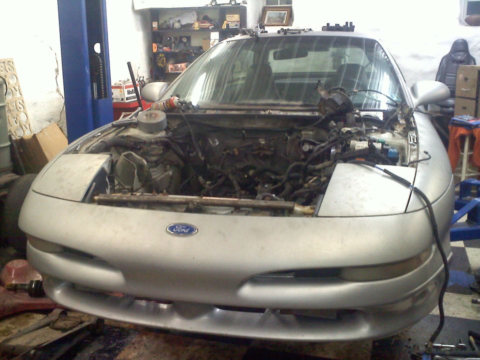 Silver 1993 Ford Probe with hood open, engine exposed, in a garage