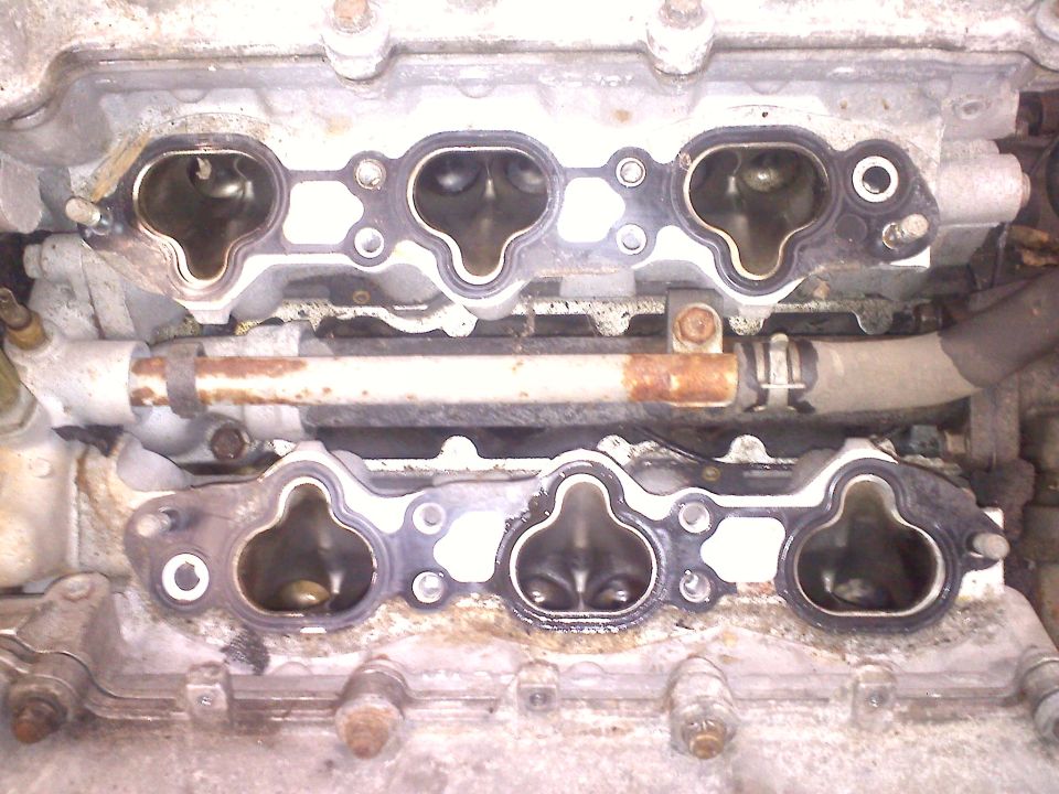 Engine intake manifold with gasket removed, showing ports and internal components