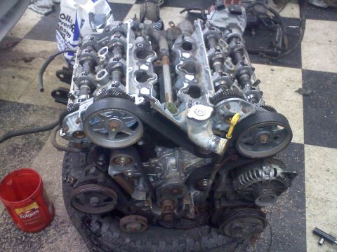 1993 Ford Probe - Engine components are visible, including camshafts and timing belts, with a tire and coffee can in the foreground.