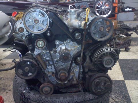 1993 Ford Probe - Engine assembly with visible belts, pulleys, and alternator. Water pump is at the top center of the engine.