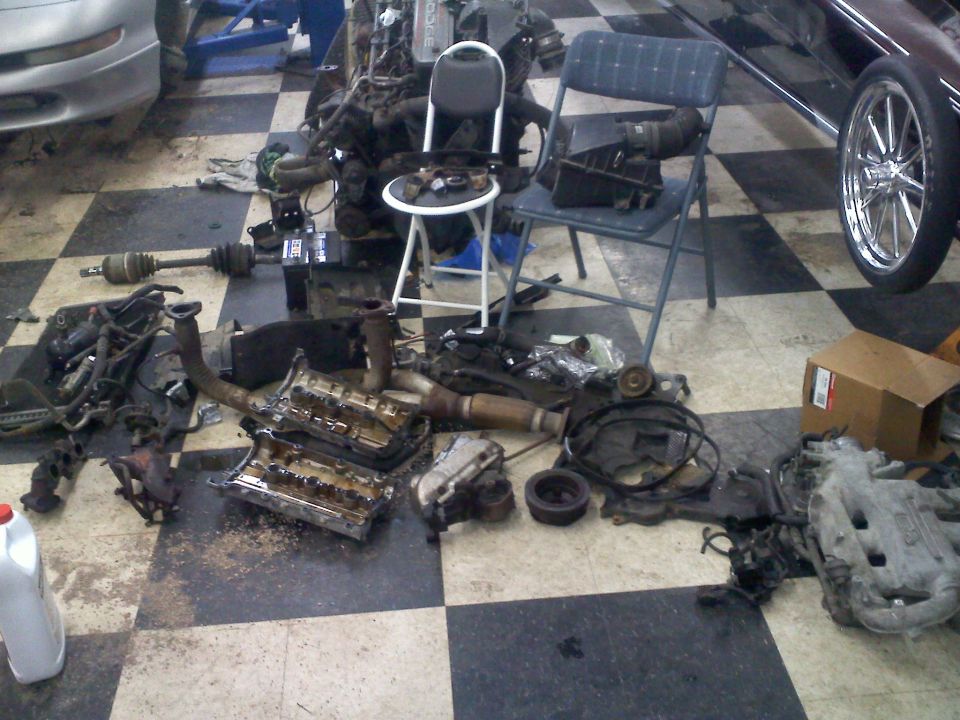 Disassembled engine parts on a checkered garage floor