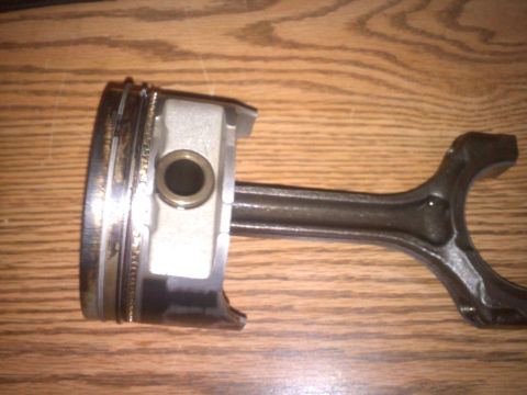 1993 Ford Probe - Engine part: piston and connecting rod assembly shown on a wooden background.