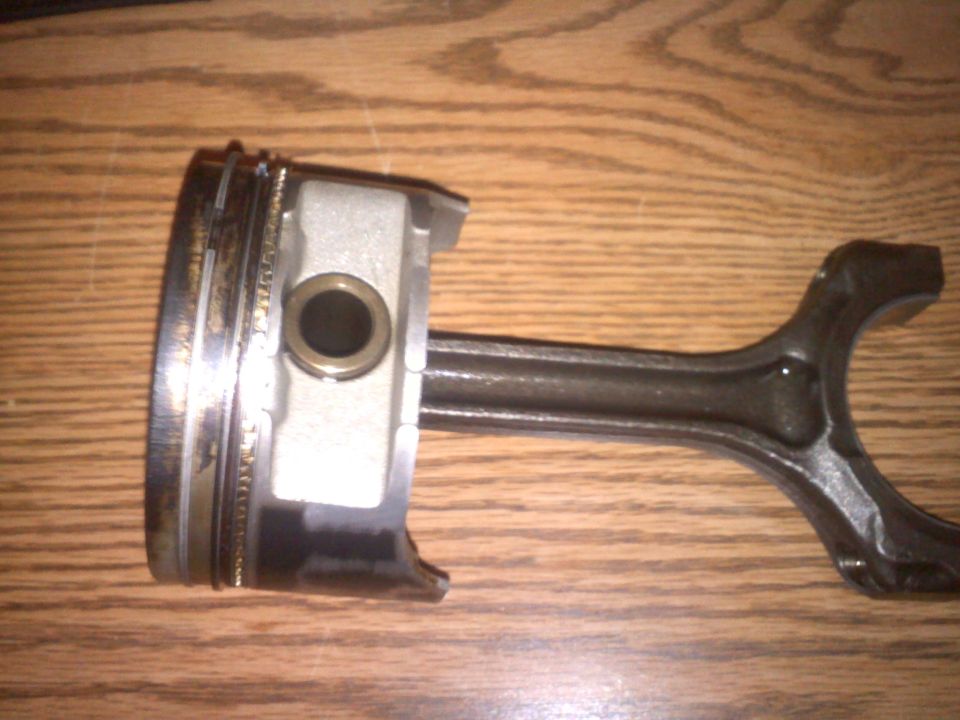 Piston with rings and connecting rod assembly on a wooden surface