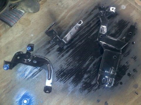 1993 Ford Probe - Three metal brackets, likely automotive parts, are shown after being painted black.