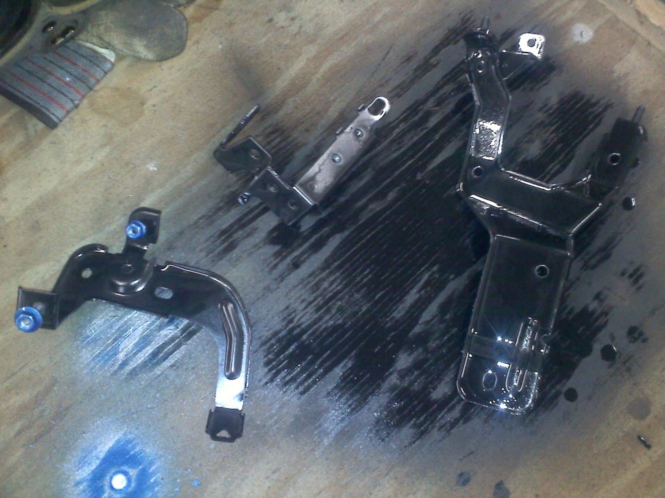 Three black painted metal brackets on a wooden surface