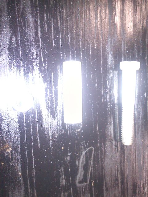 1993 Ford Probe - Two bolts and a cylindrical part are shown on a dark, textured surface.