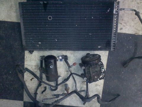 1993 Ford Probe - Car AC parts including a compressor, receiver-drier, and condenser are displayed on a checkered surface.