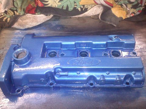1993 Ford Probe - A blue Ford valve cover is shown, likely after being painted, with visible bolt holes and threaded ports.