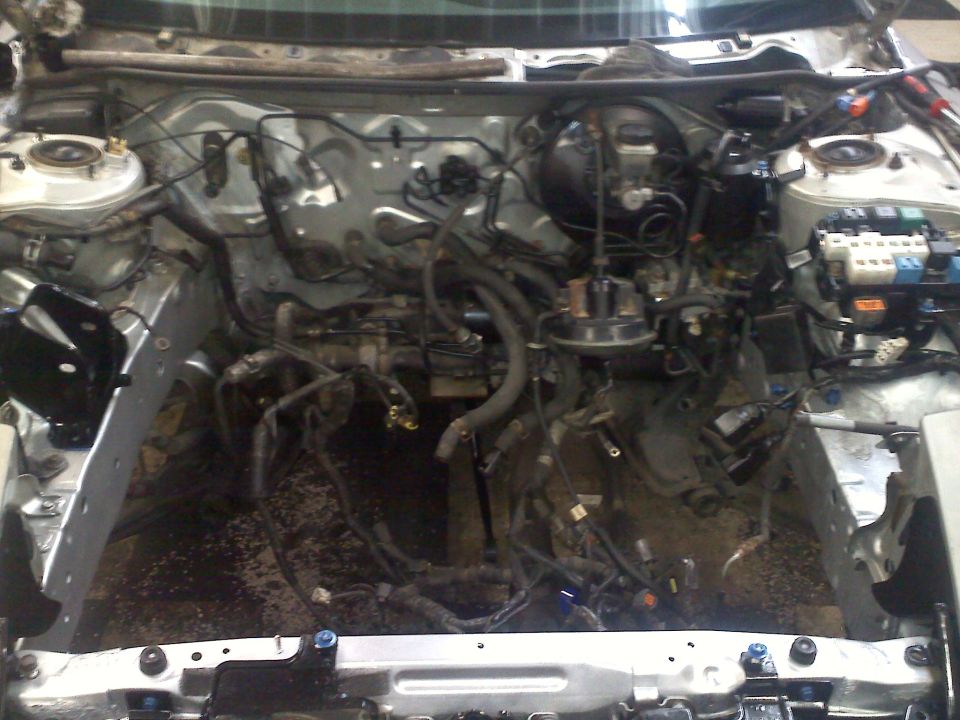 Empty engine bay showing wiring harnesses, brake booster, and suspension components