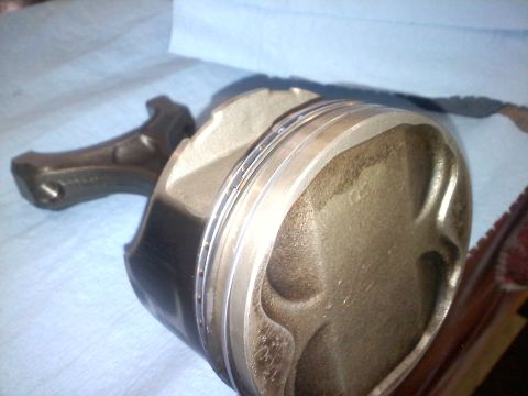 1993 Ford Probe - A close-up view of a disassembled engine piston and connecting rod assembly.