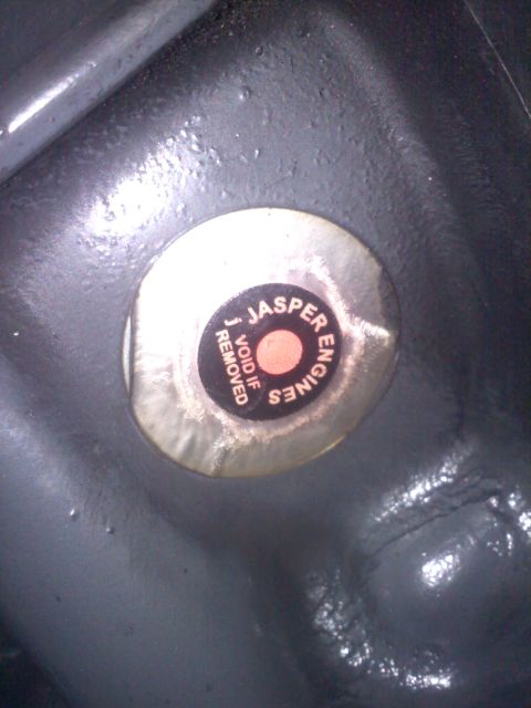 1993 Ford Probe - Close-up of a Jasper Engines sticker with 'VOID IF REMOVED' text on a dark, textured metal surface.