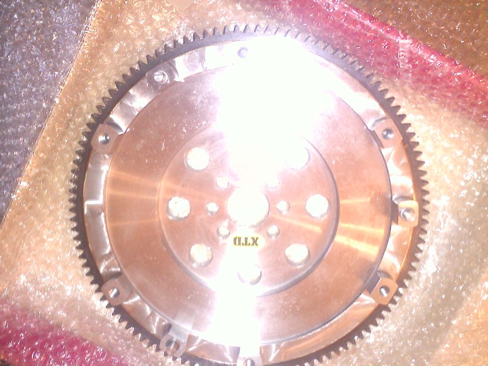 Metal flywheel with gear teeth and bolt holes, some text visible