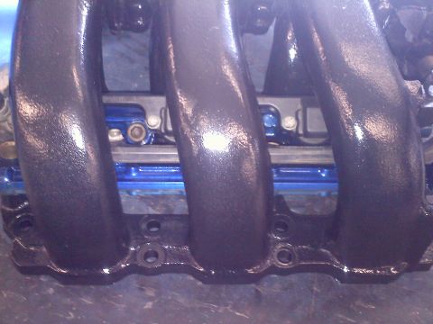 1993 Ford Probe - This is a close-up view of an engine's intake manifold, showing its textured black finish and mounting holes.