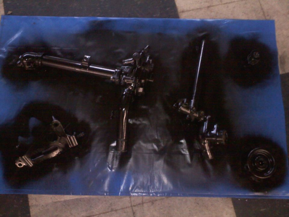 Black painted automotive components on a blue tarp